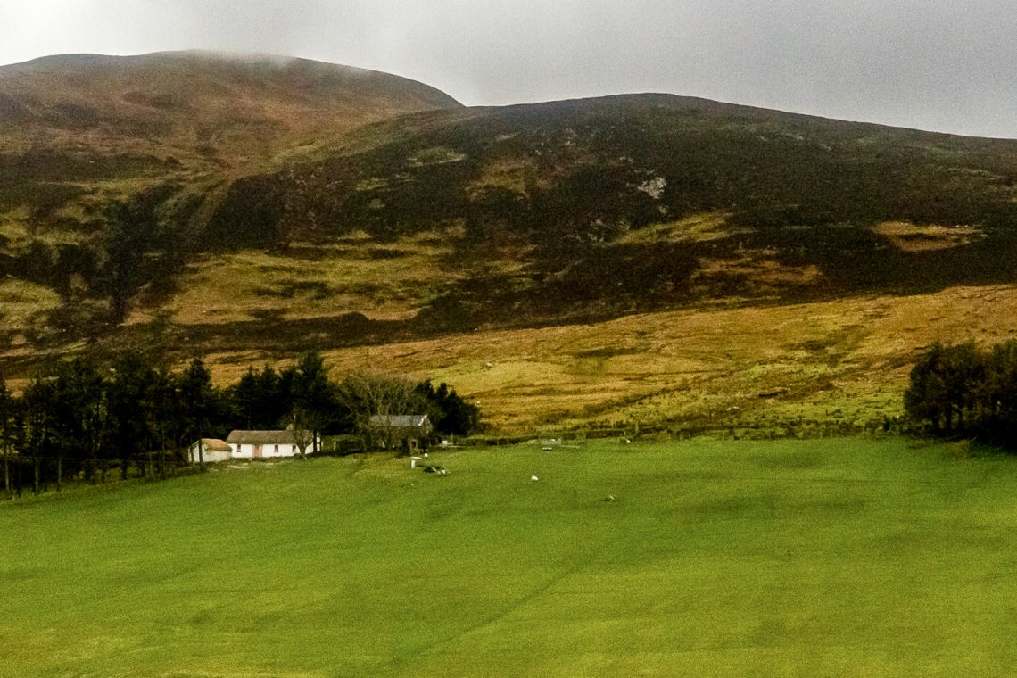 Intensively managed pasture set against degraded hillsides, illustrating land use imbalance.