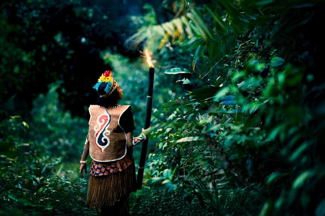 A beautiful shot of an individual carrying a flame torch as they traverse the forest. 