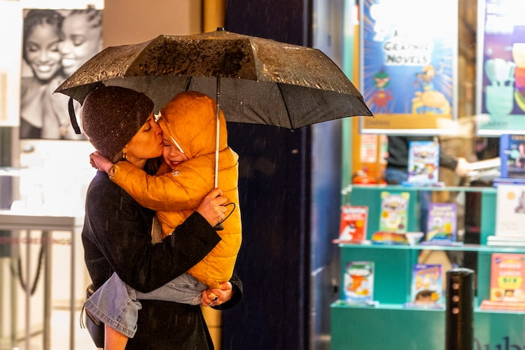 A mother shelters her child from relentless winter rain. What was once an occasional downpour has become a symbol of Ireland’s changing climate and human resilience amid worsening storms.