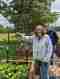 A woman holding a freshly picked radish in the garden, with a man in the community garden.